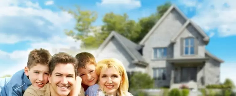 family laying in grass infort of house
